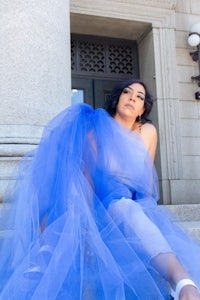 a woman in a blue tulle dress sitting on steps