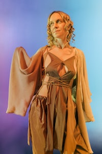 a woman in a costume standing in front of a colorful background