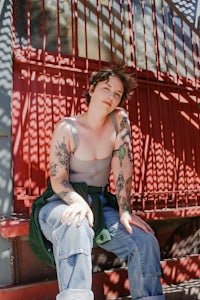 a woman with tattoos sitting on a red railing