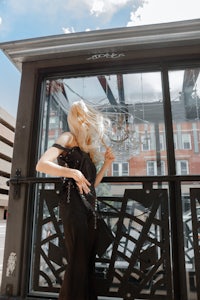 a woman in a black dress standing in front of a glass door