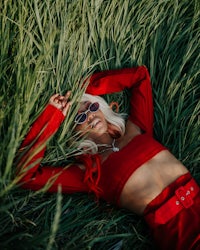 a woman in a red outfit laying in tall grass