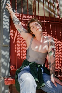 a woman with tattoos posing in front of a fence