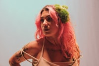 a woman with pink hair and tattoos posing for a photo