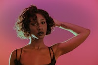 a black woman posing in front of a colorful background