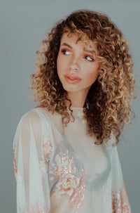 a young woman with curly hair posing for a photo