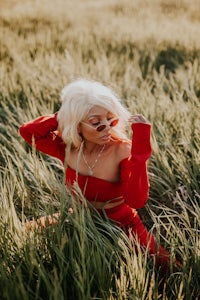 a woman in red sitting in tall grass