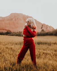 a woman in a red jumpsuit standing in a field