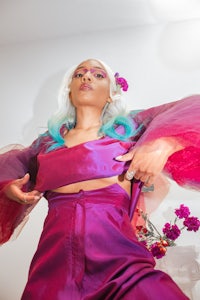 a woman in a purple dress posing in front of flowers