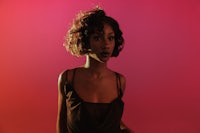 a black woman posing in front of a pink background