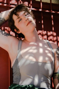 a woman with tattoos laying on a red wall