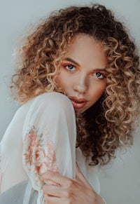 a young woman with curly hair posing for a photo